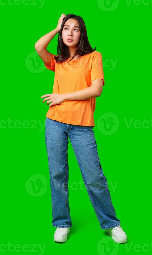 Young woman in orange shirt poses against bright green background with casual style photo