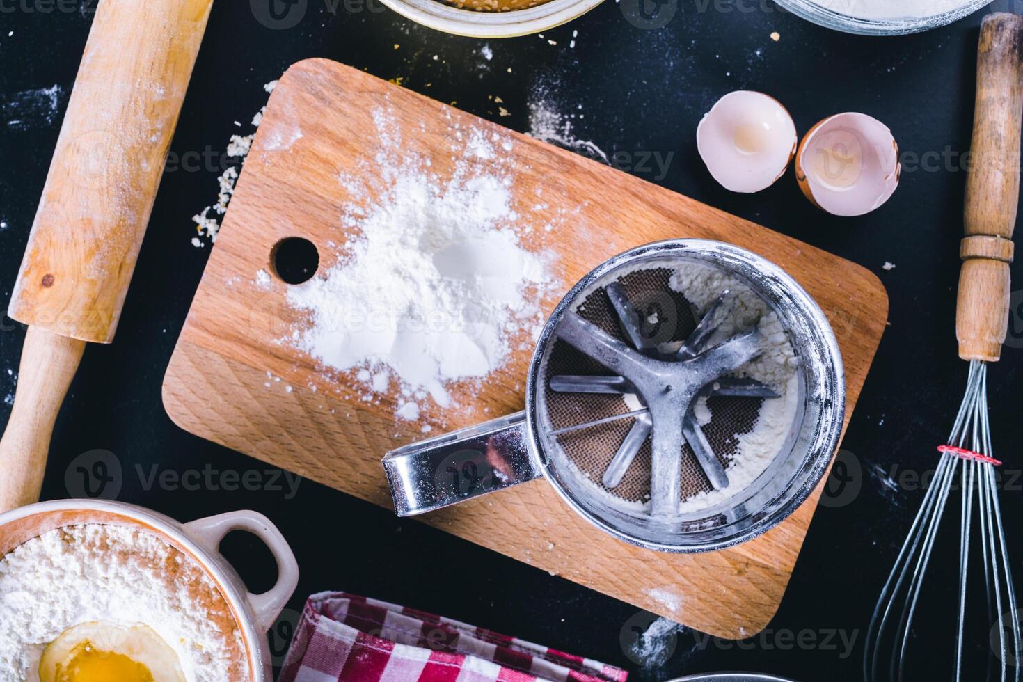 Baking dark background with blank cook book, eggshell, bread, flour, rolling pin. Ingredients for the baking. photo