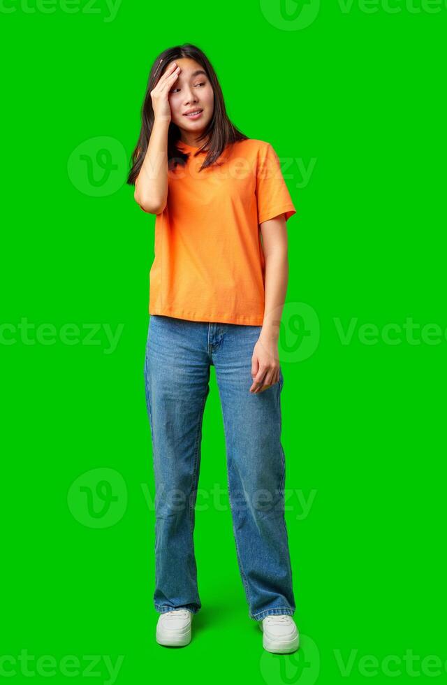 Young woman in orange shirt expressing confusion against bright green background in casual indoor setting photo