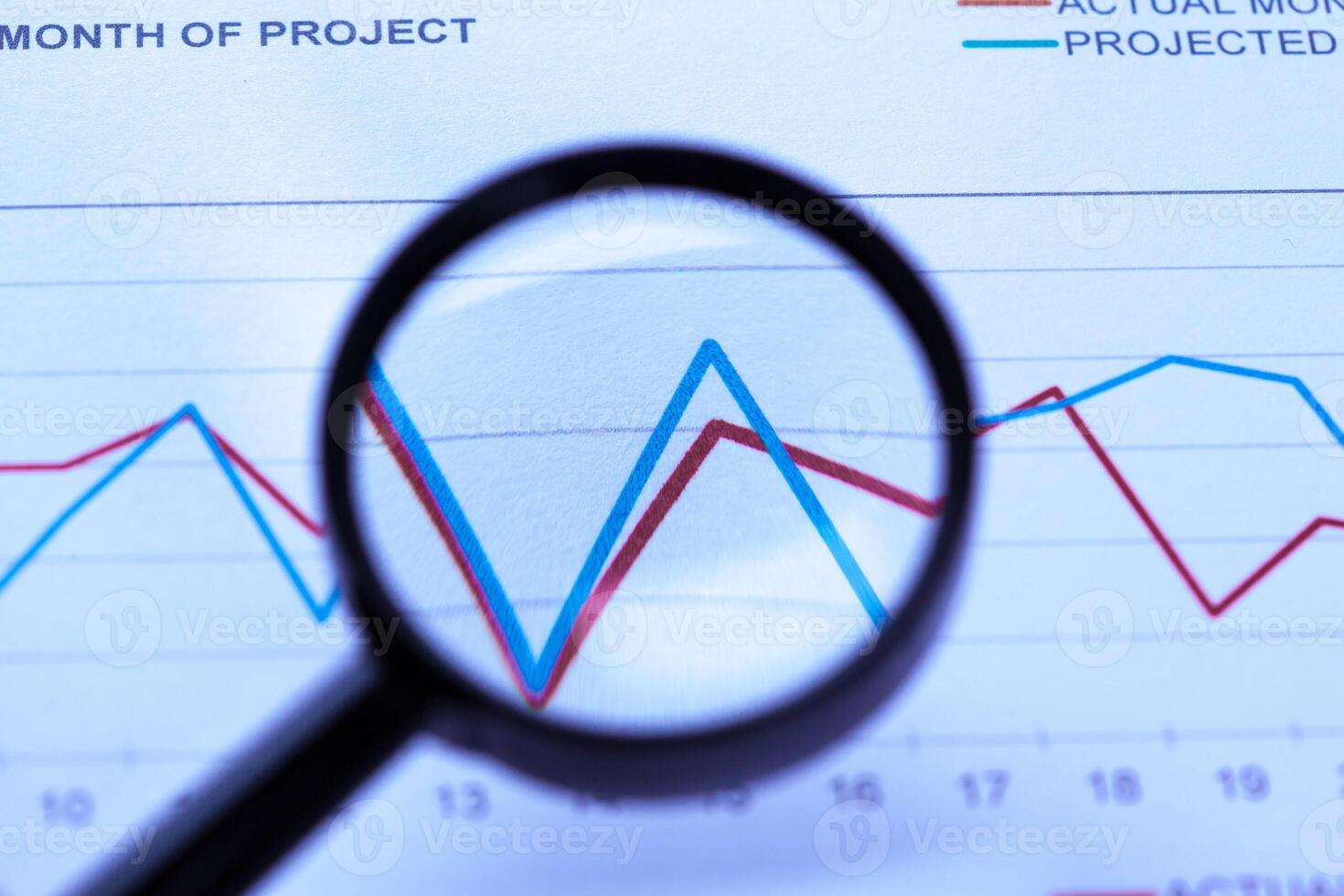 financial documents with magnifying glass over them photo