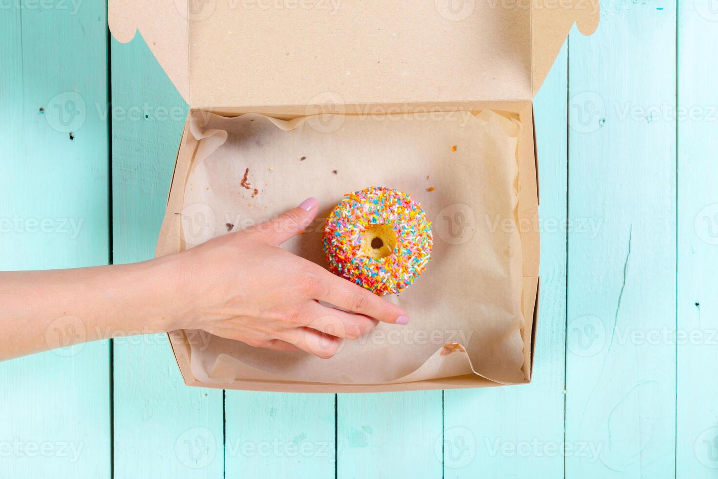 Donuts in box on wooden table. Top view photo