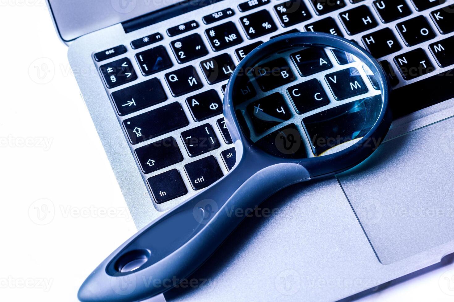 Closeup images of magnifying glass on laptop keyboard photo
