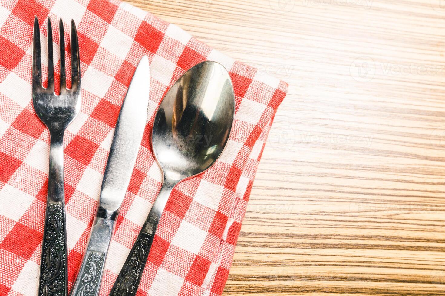 Fork and table knife on red gingham tablecloth photo