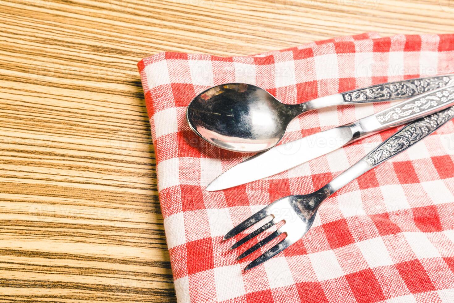 Fork and table knife on red gingham tablecloth photo
