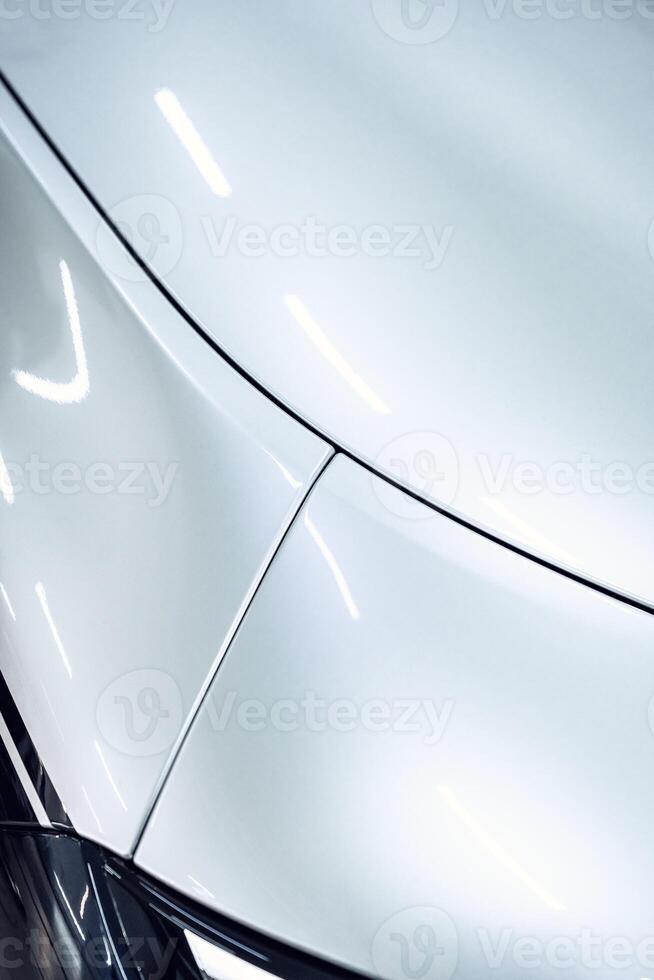Sleek white car body with smooth curves and polished finish in a well-lit garage setting photo
