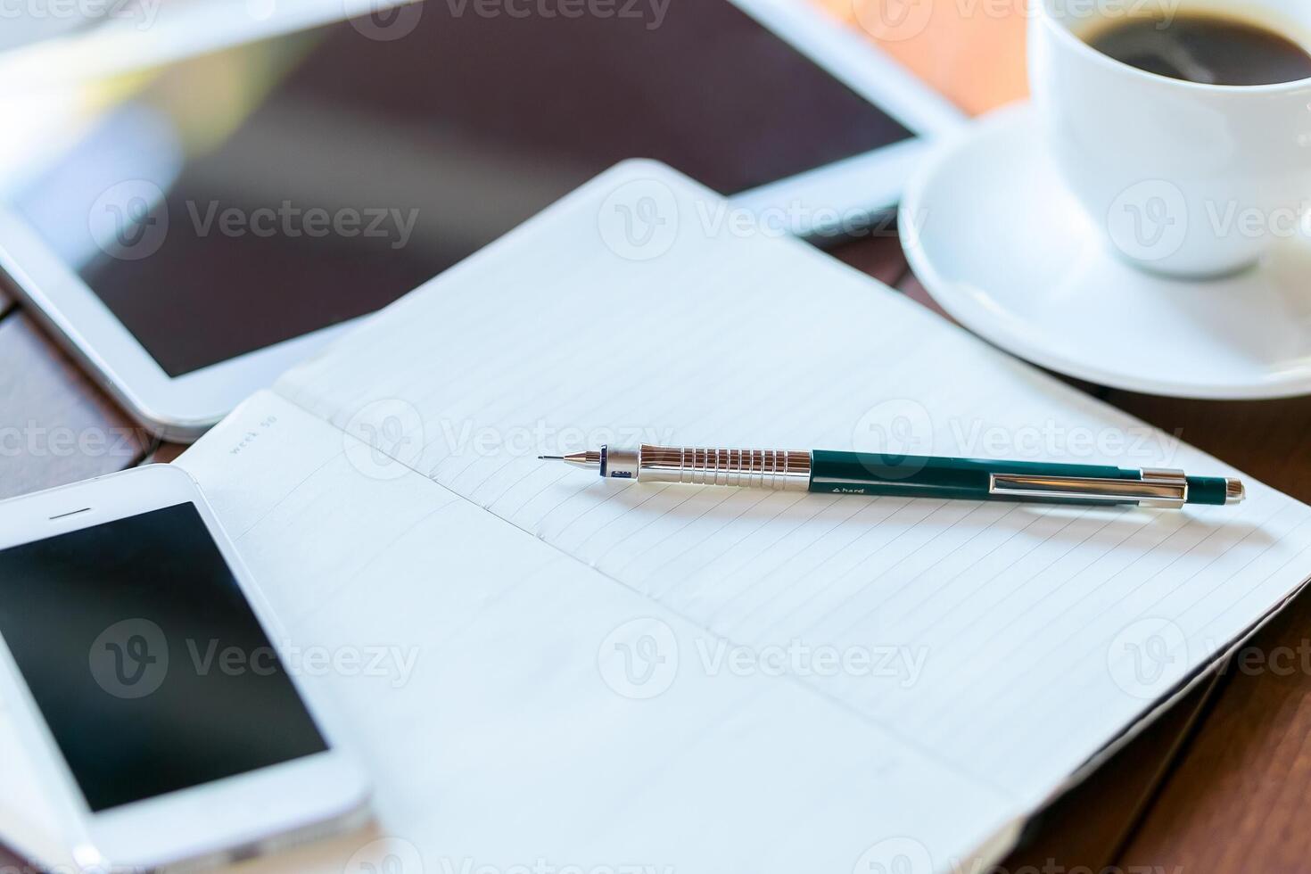 Desk workspace with a notepad, tablet, smartphone, pen, and a cup of coffee during a productive morning photo