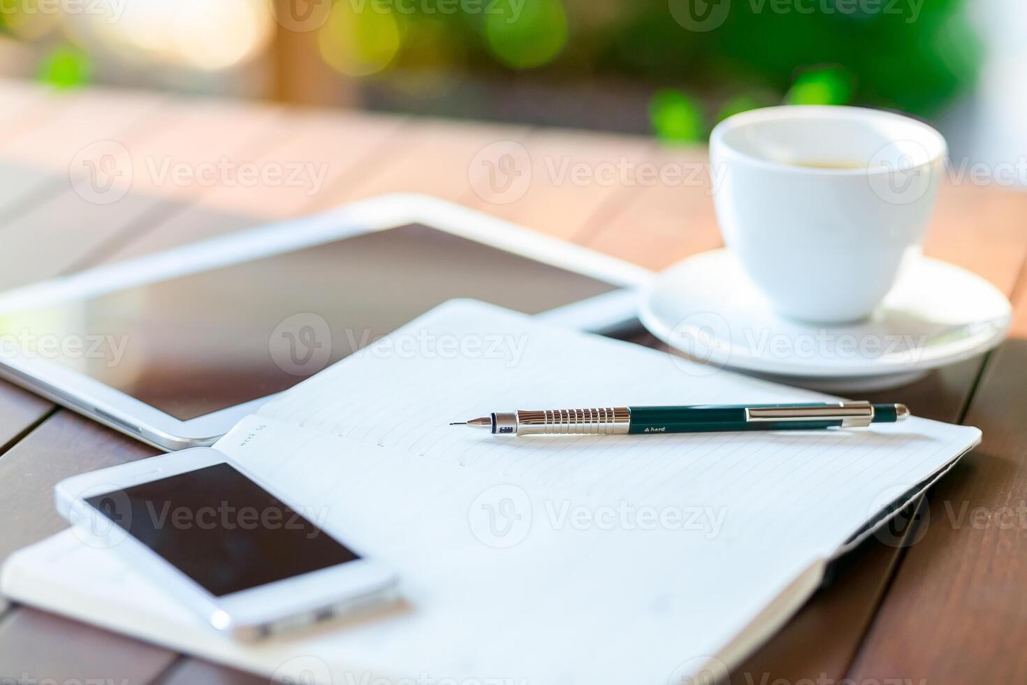 Workspace setup with tablet, notebook, smartphone, and cup of coffee during morning hours in a cozy environment photo