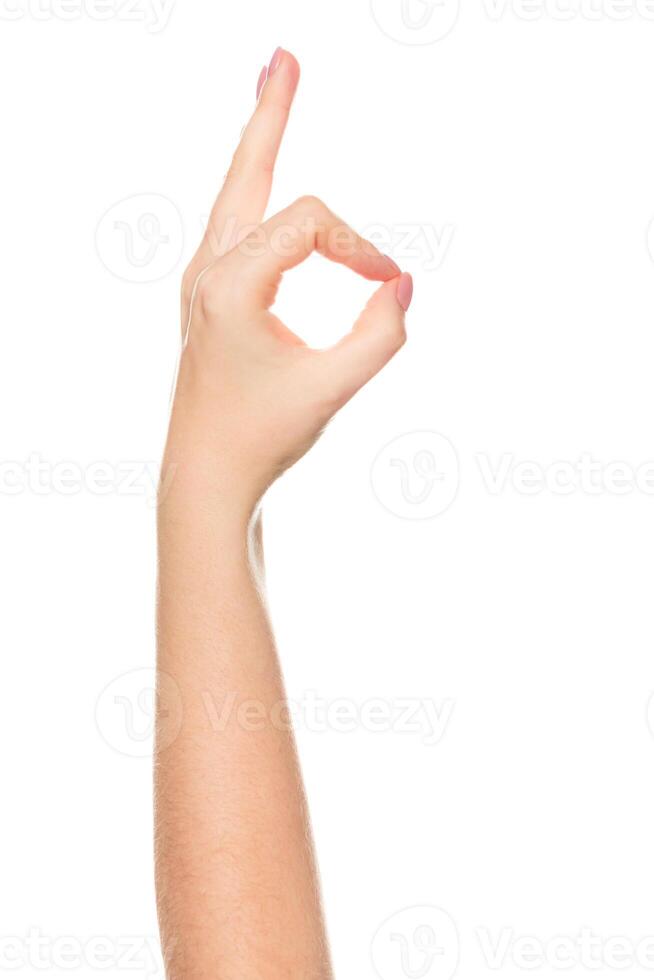 Hand gesture showing approval with fingers in an okay position against a plain background during daylight photo