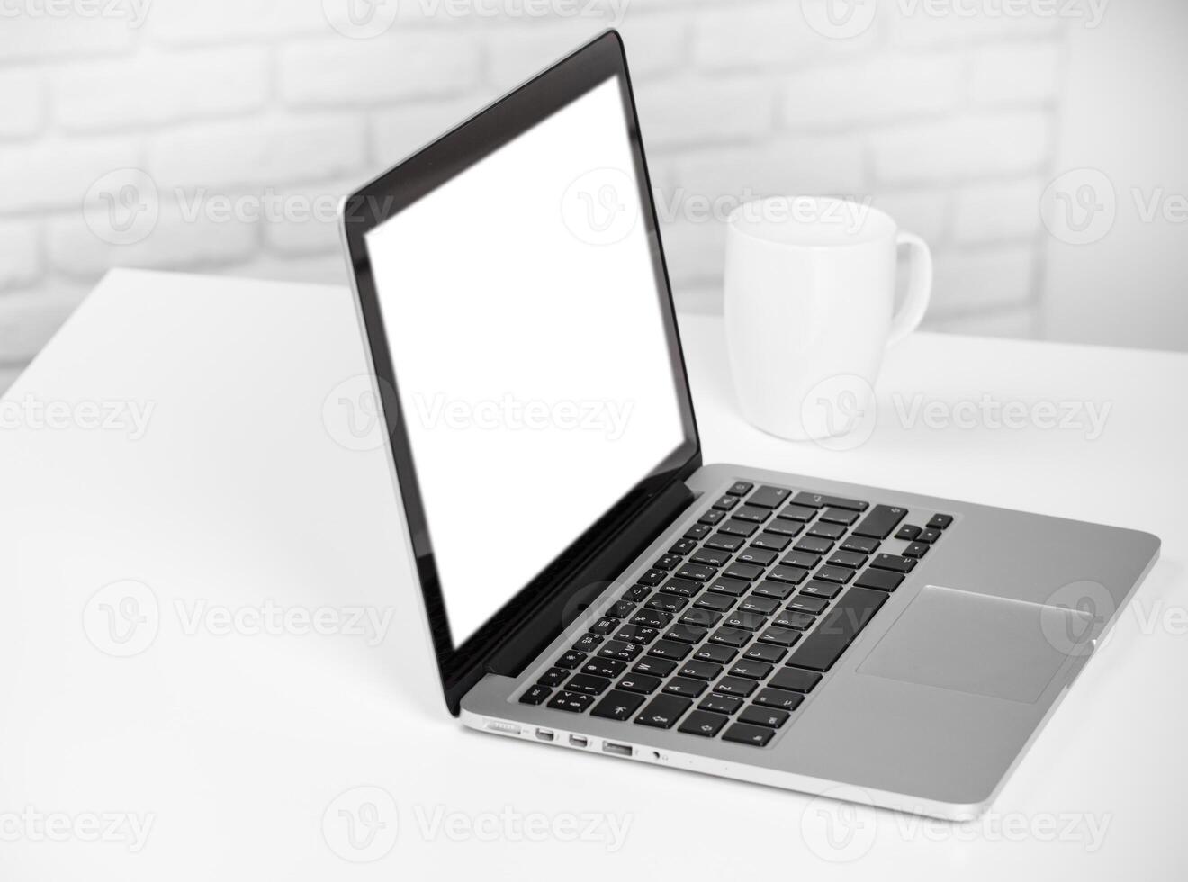 Laptop on a desk with a blank screen and a coffee mug in a minimalistic workspace photo