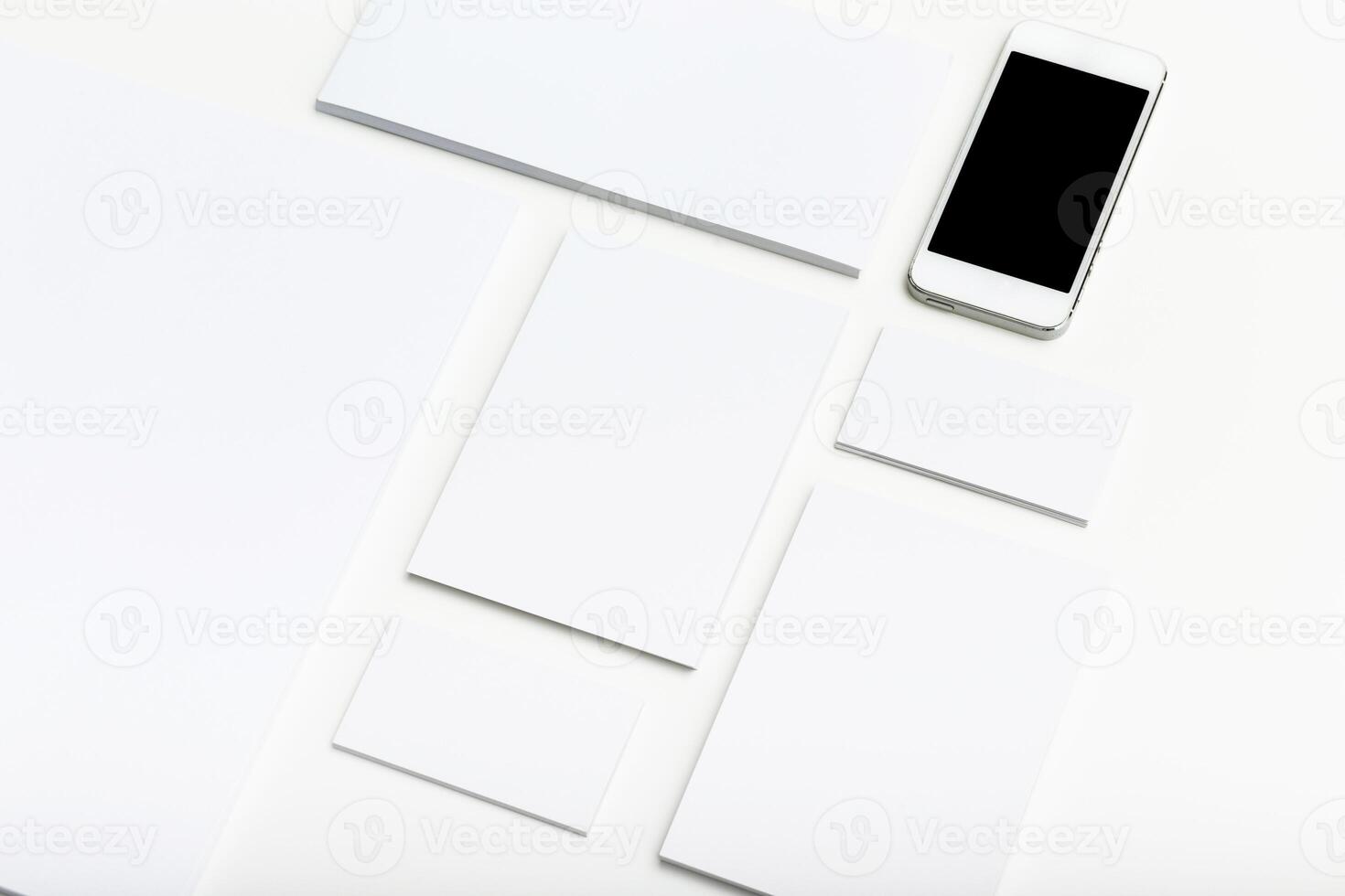 Clean workspace layout with blank papers and smartphone placed on white background photo