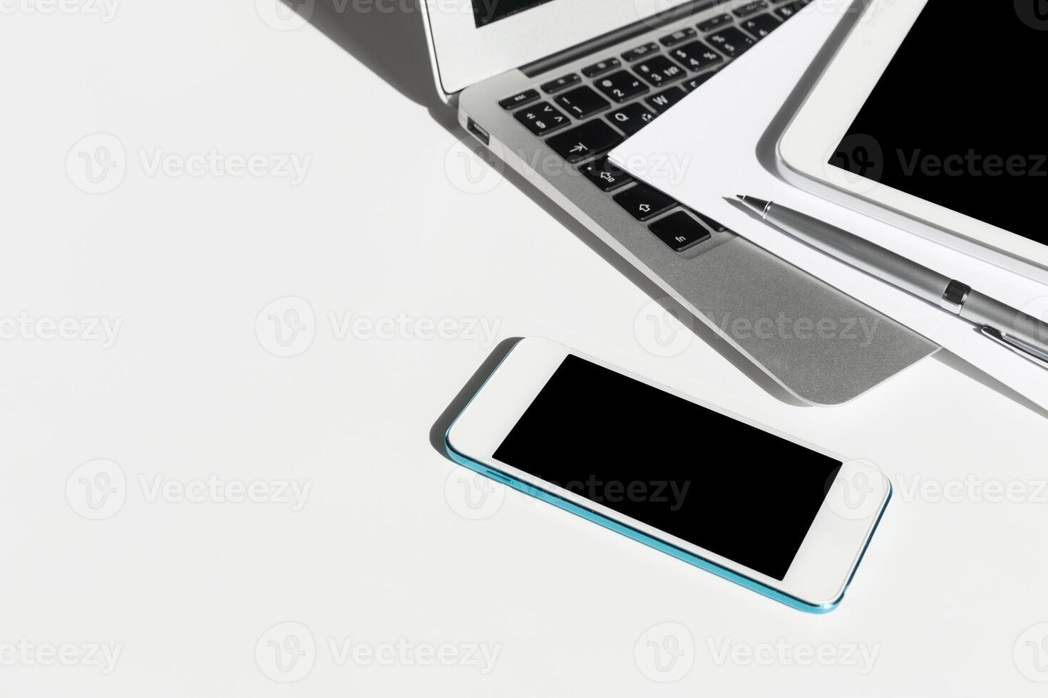 Modern workspace with laptop, tablet, smartphone, and pen arranged neatly on a white desk photo
