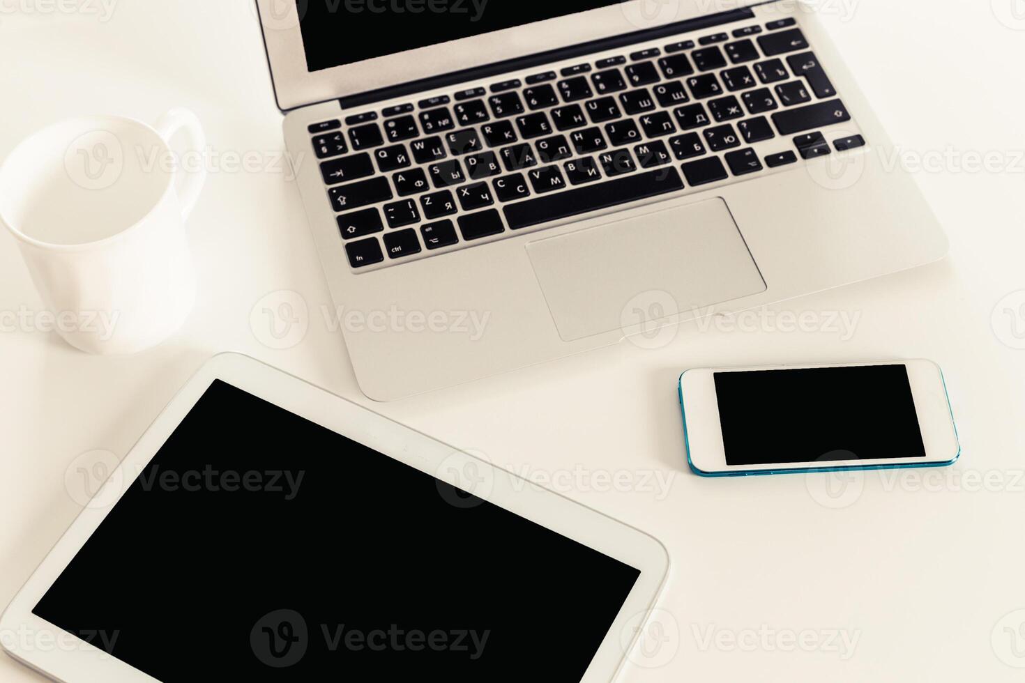 Tech devices arranged on a white table showcasing a laptop, tablet, and smartphone during a work session photo