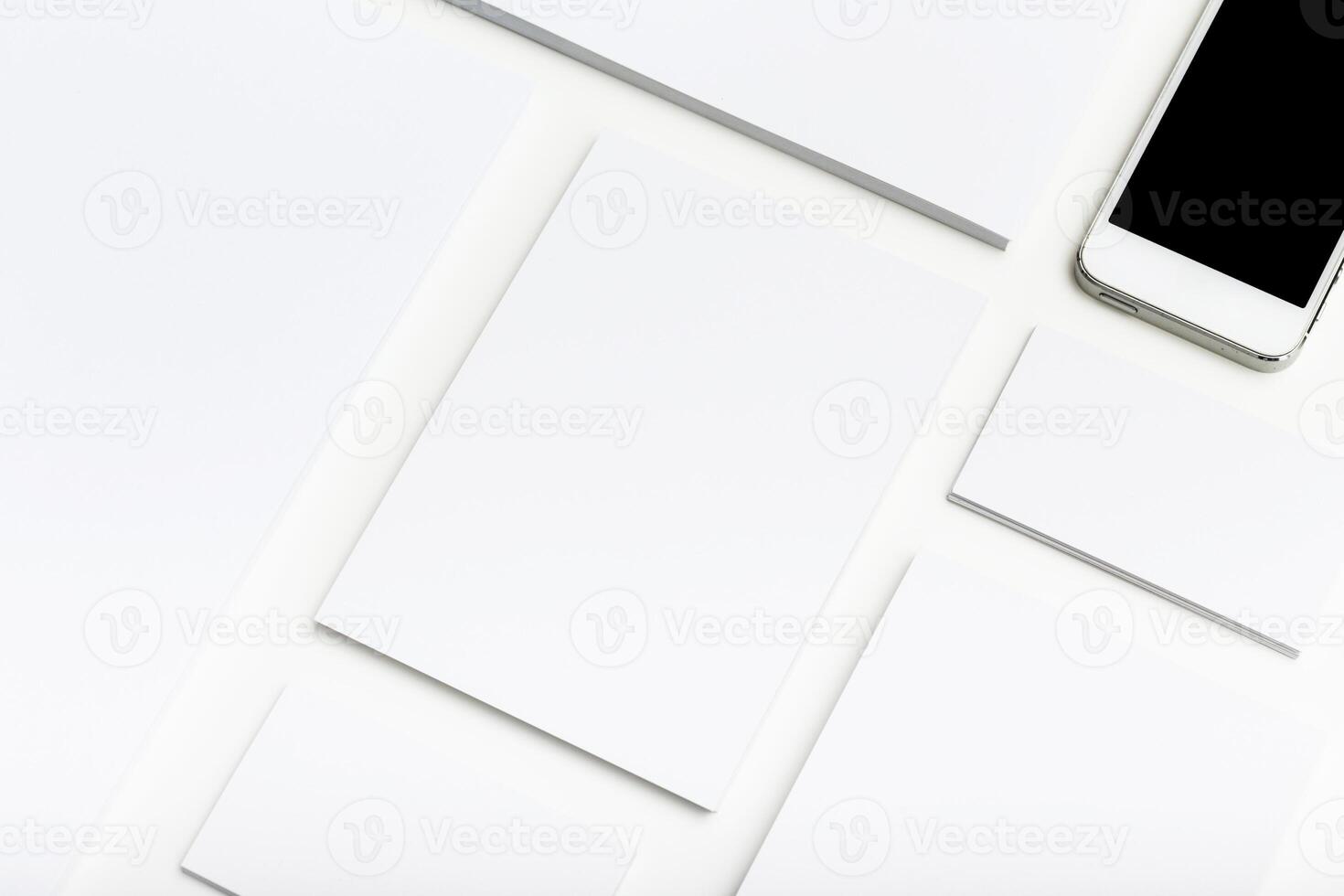 Minimalist workspace with blank papers and a smartphone on a clean white surface photo