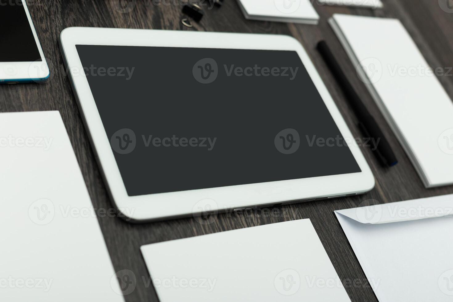 Workspace layout featuring digital tablet and stationery on a wooden desk during daylight photo