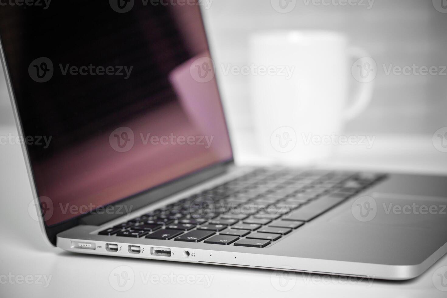 Laptop on table with cup of coffee in background creates a cozy workspace atmosphere photo