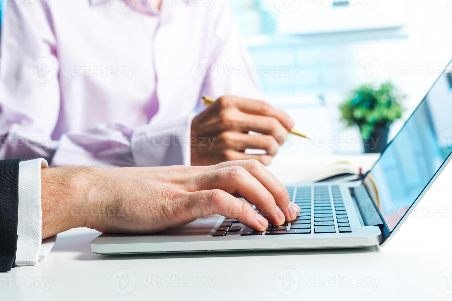 Collaboration between professionals at a workspace while engaging in a discussion and using a laptop for project updates photo