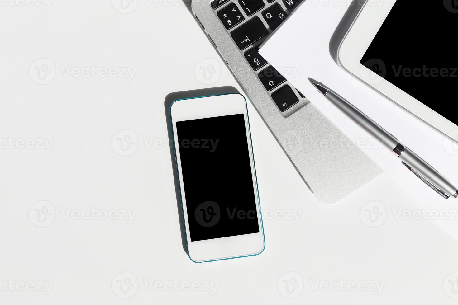 Workstation setup with smartphone, tablet, and laptop on minimalist desk during modern office hours photo