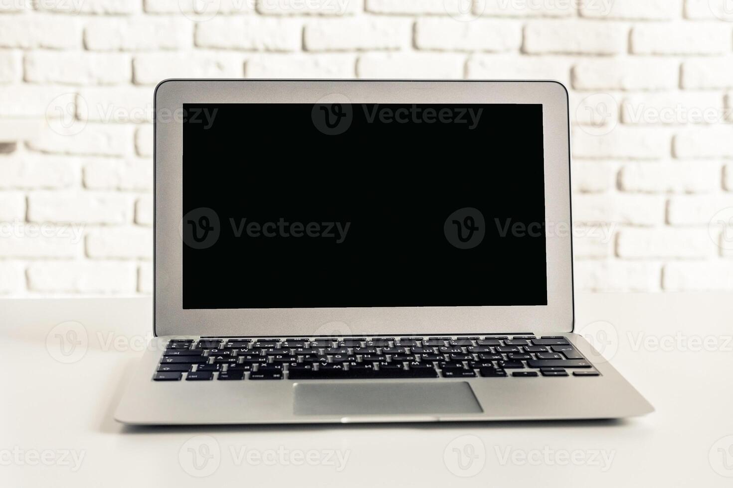 Modern laptop on a clean workspace with a white brick wall background during daytime photo