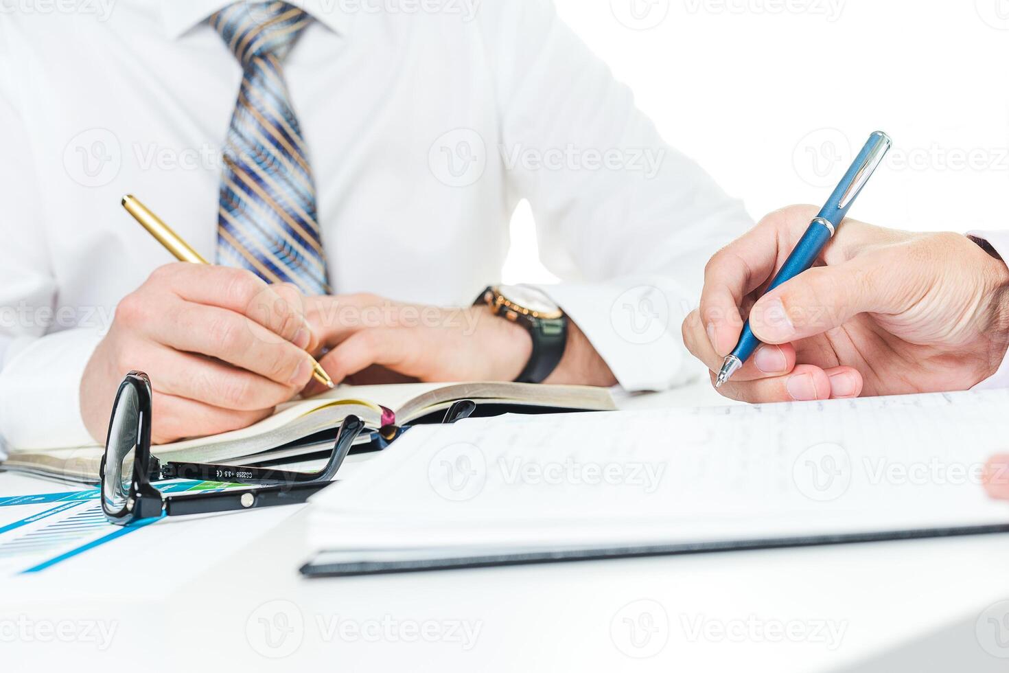 Two professionals discussing important documents at a bright workspace while taking notes and signing papers photo