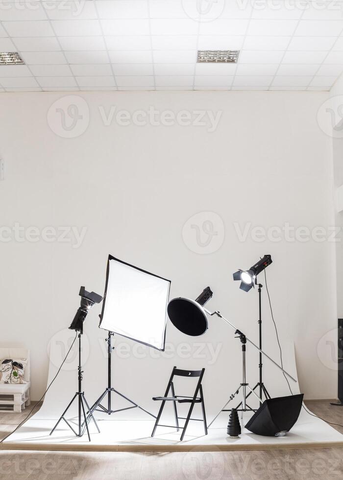 Studio setup with lighting equipment and chair ready for a creative session near a white wall in a bright space photo