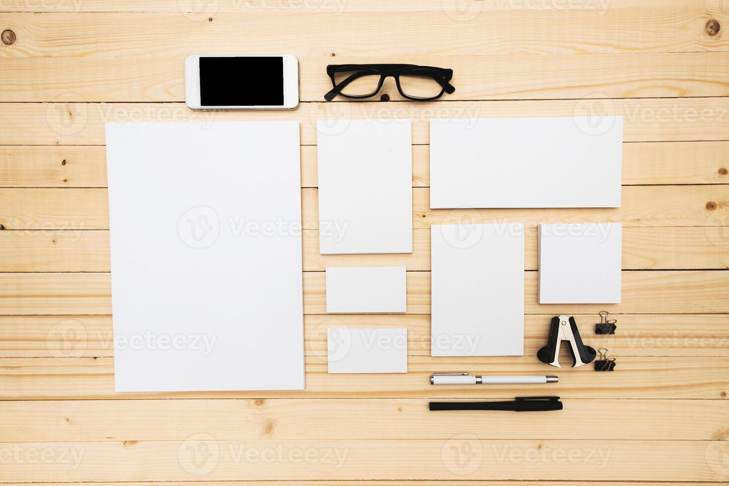 Workspace setup featuring stationery, a smartphone, and glasses on a wooden table photo