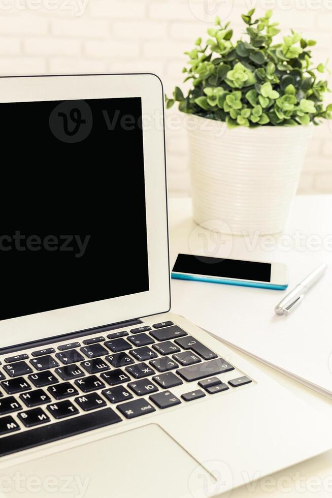 Workspace setup with laptop, smartphone, stationery, and potted plant showcasing modern productivity for remote work photo