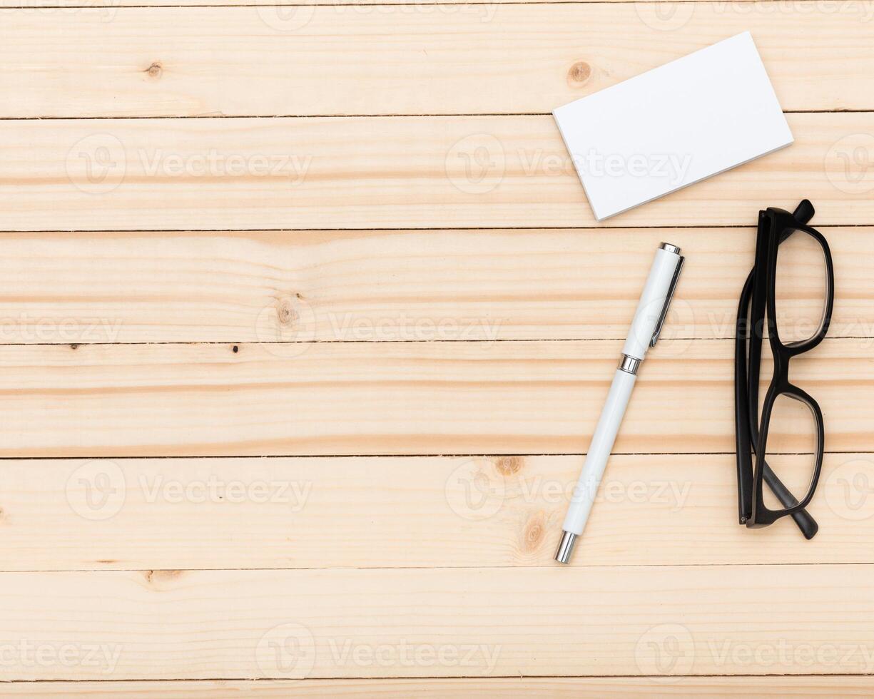 Workspace setup with pen, glasses, and blank card on wooden surface for creative ideas and notes photo