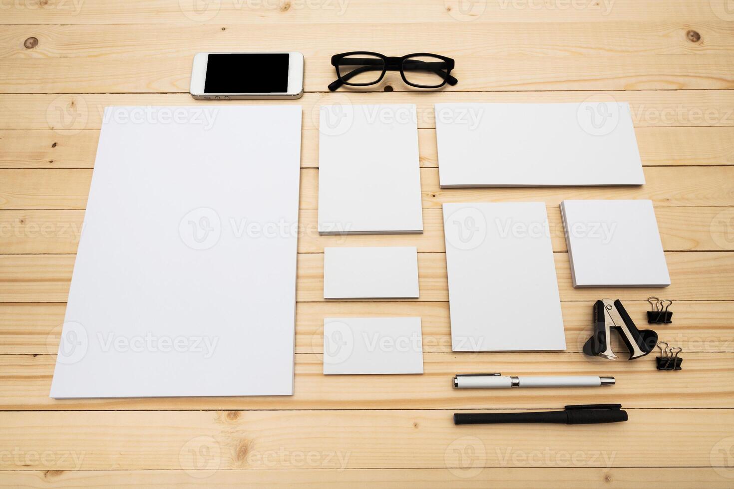 Collection of stationery items and a smartphone arranged on a wooden desk for creative work or planning tasks photo