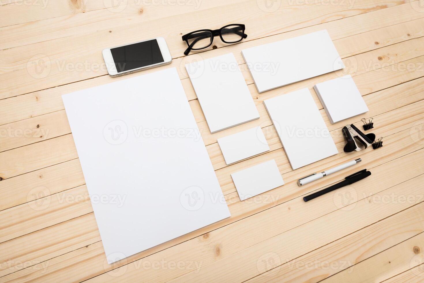 Workspace with blank paper, smartphone, and glasses on wooden table in a creative setting photo