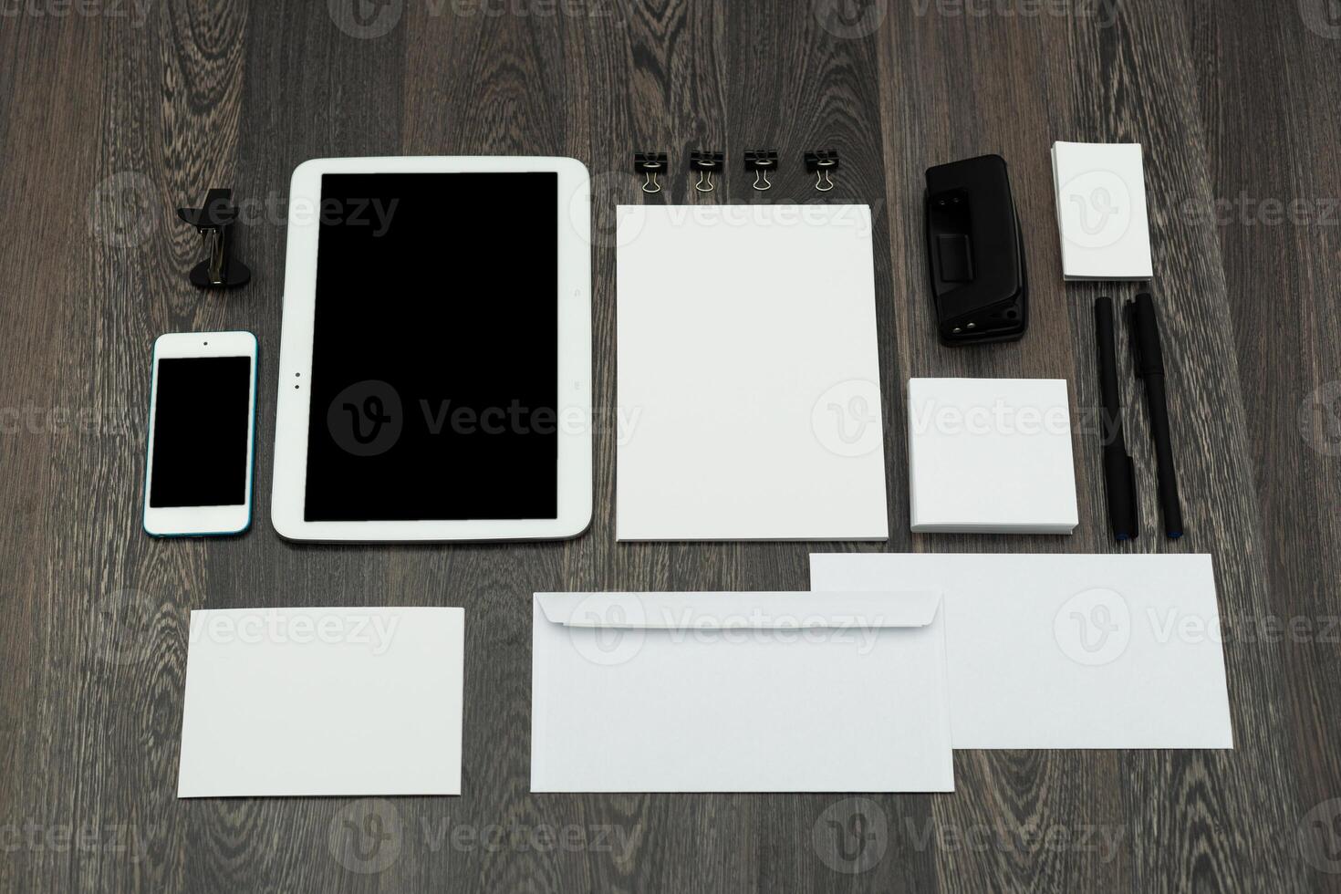 Workspace arrangement with digital and stationery items on wooden table surface during daylight hours photo