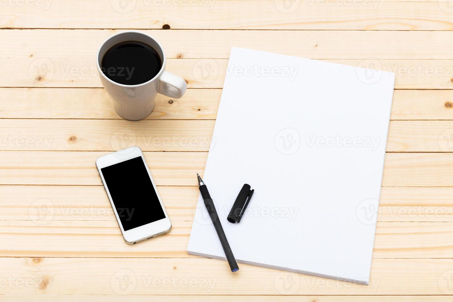 Workspace with coffee, smartphone, and blank paper on wooden table during morning hours photo