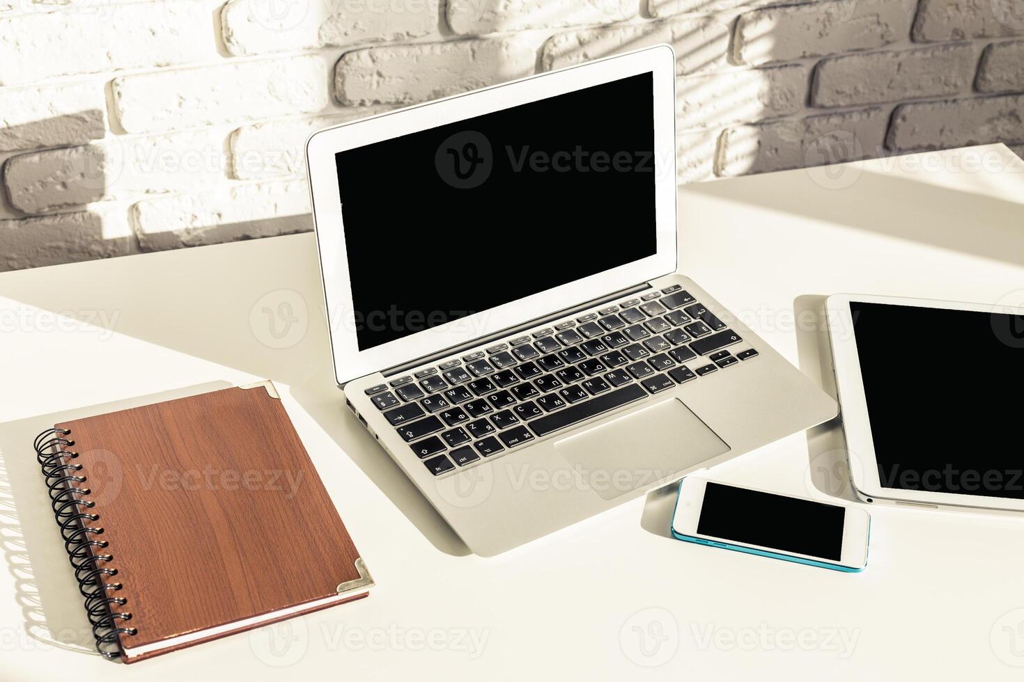 Modern workspace setup featuring a laptop, tablet, smartphone, and notebook on a clean desk with a minimalistic design photo