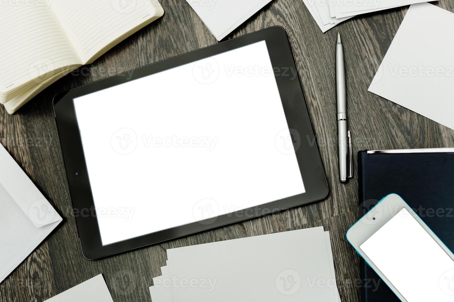 Digital workspace with tablet, pen, and blank papers on wooden desk during a creative brainstorming session photo