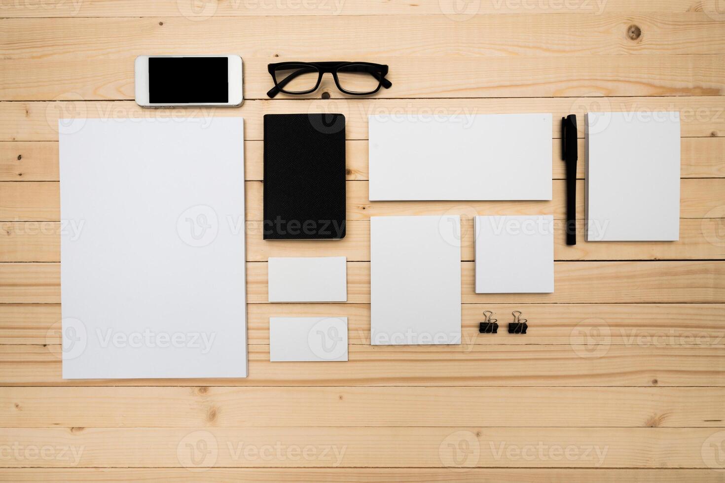 Stationery arrangement on a wooden desk with glasses and a smartphone in a well-lit workspace photo