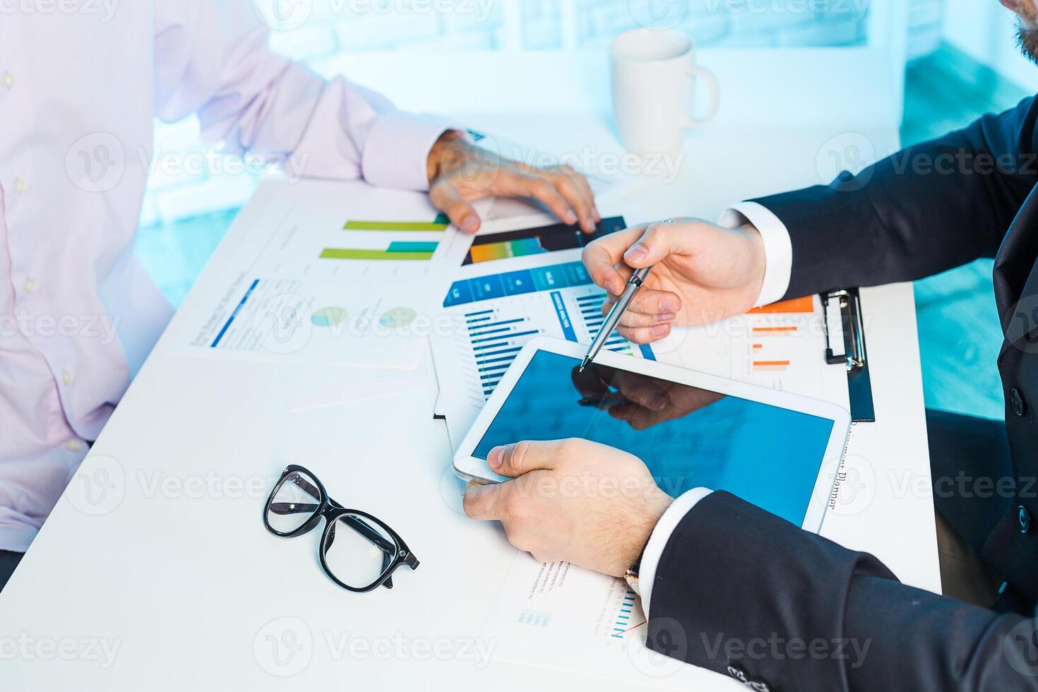 Business professionals analyze data and discuss strategies during a meeting at an office workspace in bright lighting photo