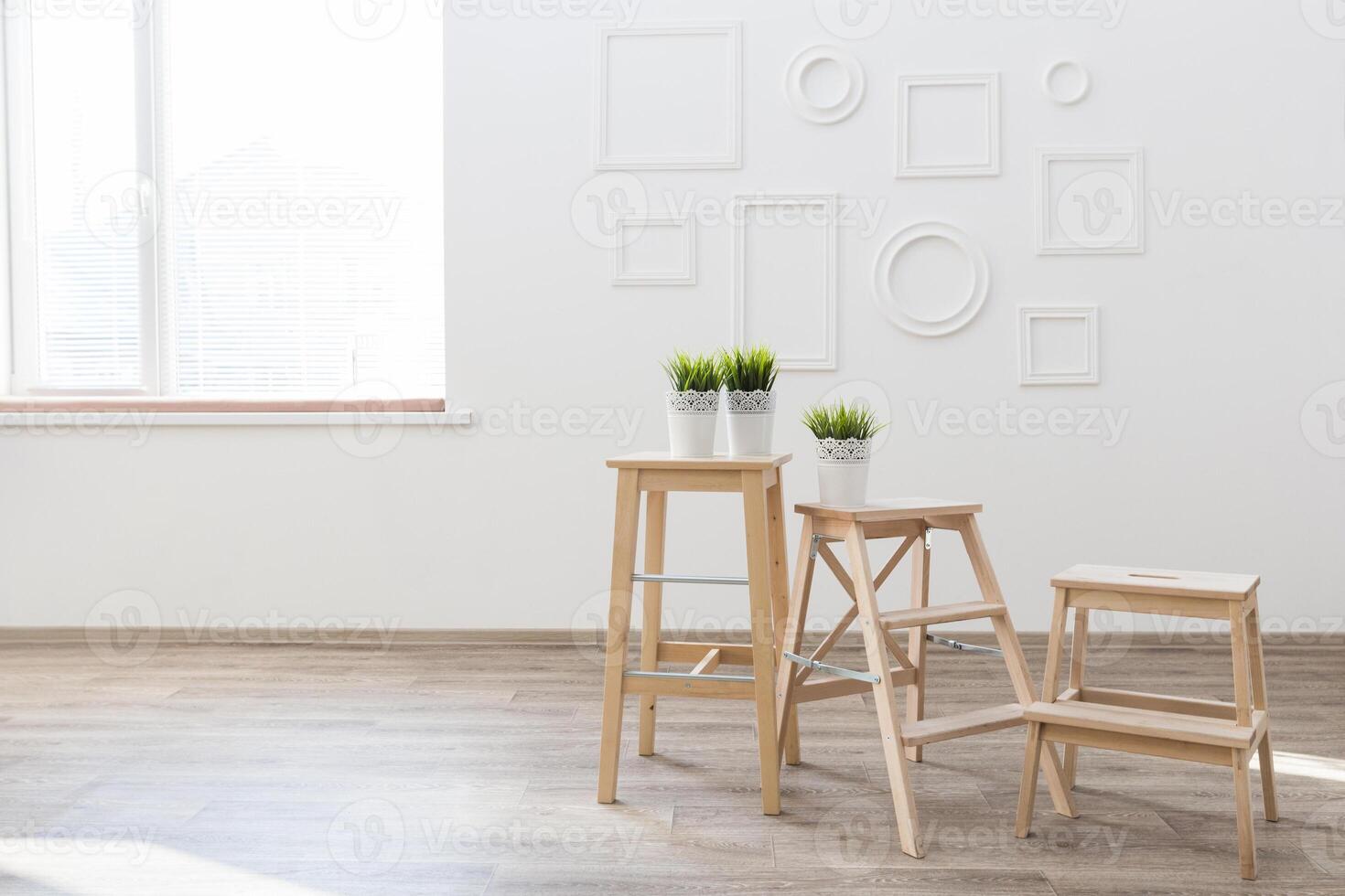 Stylish minimalist interior featuring wooden stools and potted plants in a bright sunny room photo