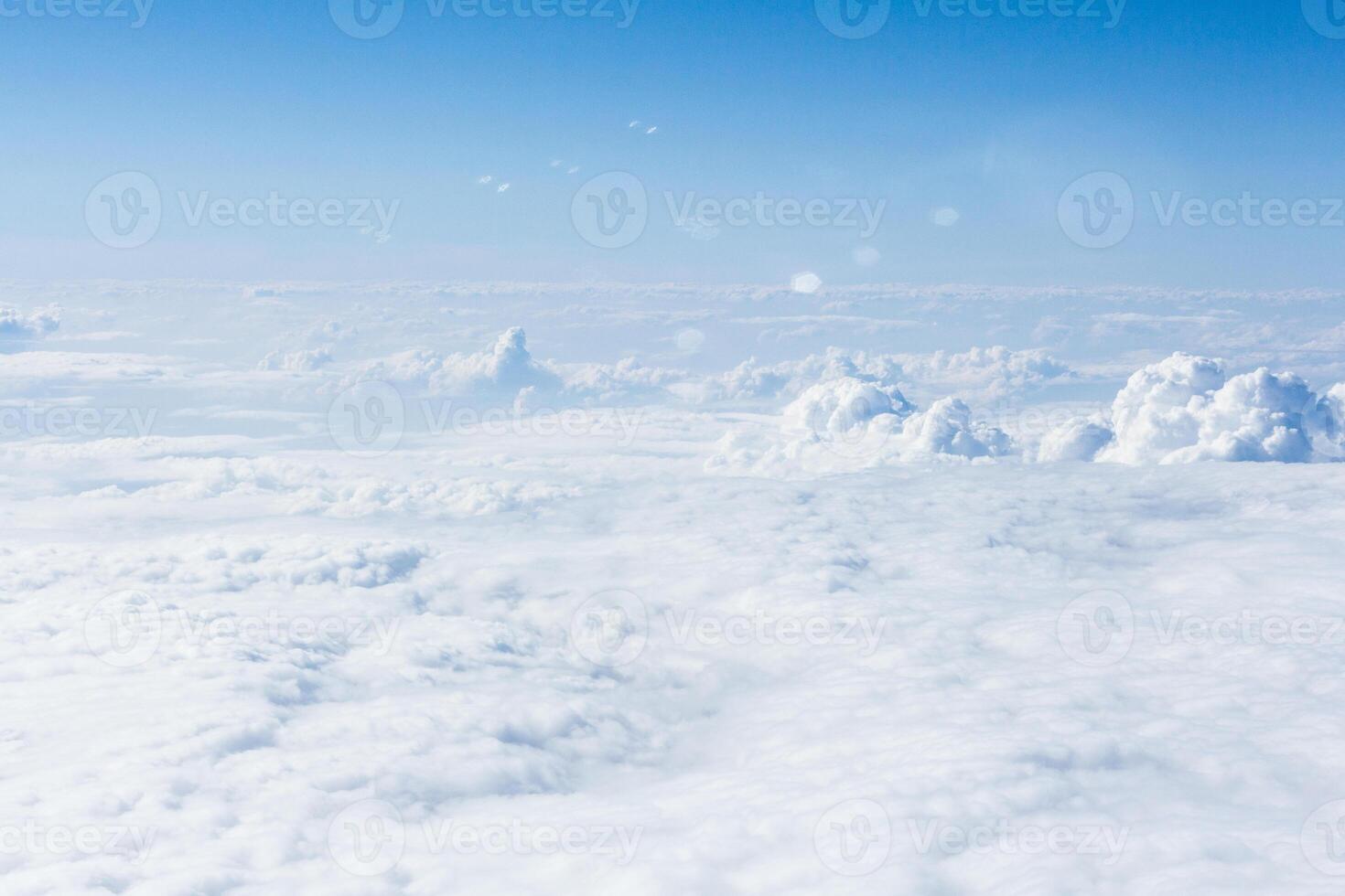 Cloudy horizon viewed from an airplane at cruising altitude under bright blue sky photo