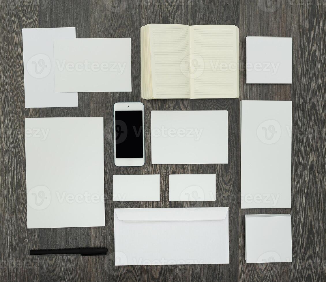 Clean and minimal workspace layout featuring blank stationery and a smartphone on a wooden desk photo