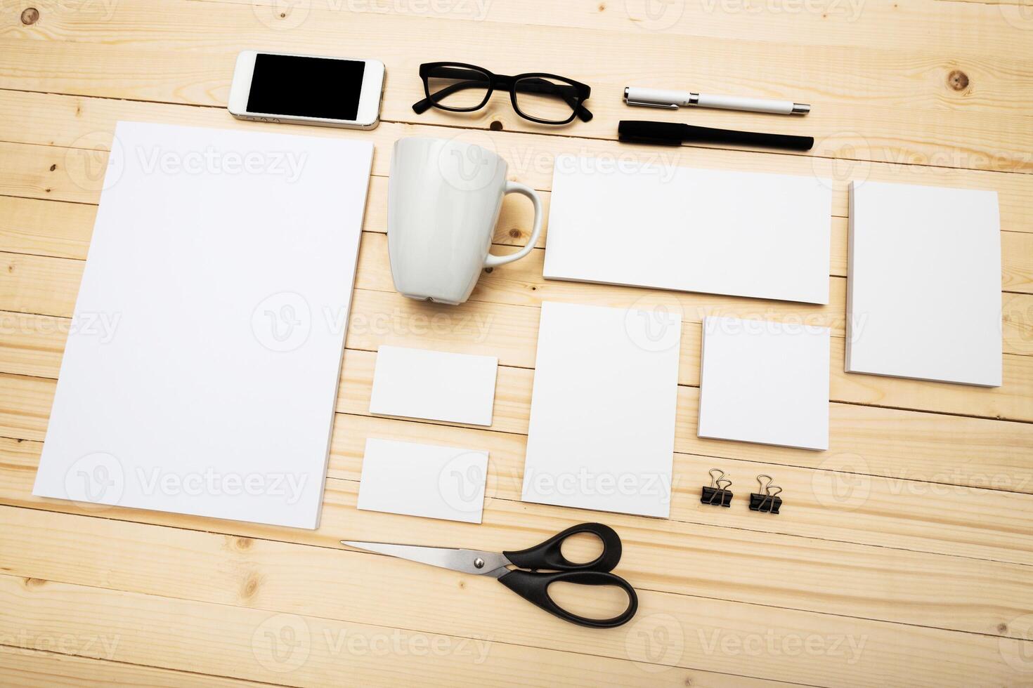 Workspace arranged with stationery items and blank papers on a wooden table during the day photo
