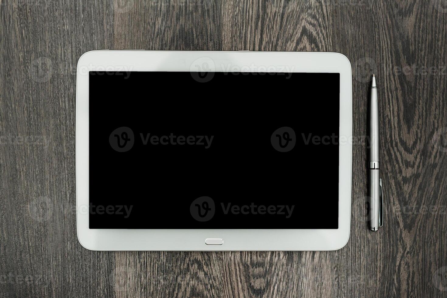 Blank tablet and pen on wooden surface ready for creative work and note-taking during a productive session photo