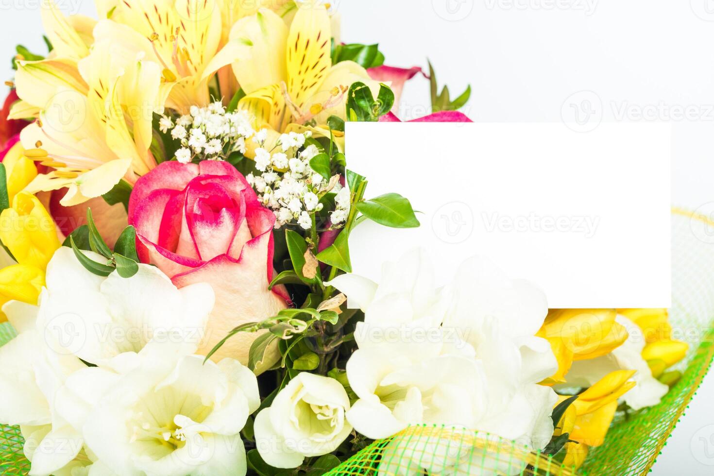Colorful bouquet featuring a variety of flowers and a blank card for personal messages in a bright setting photo