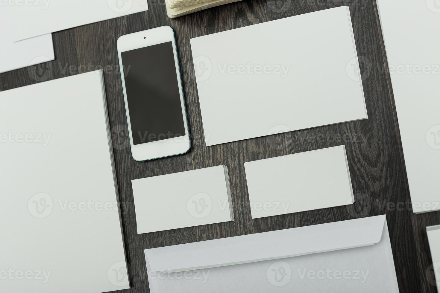 Collection of blank stationery and a smartphone on a wooden surface for creative design ideas and office organization photo