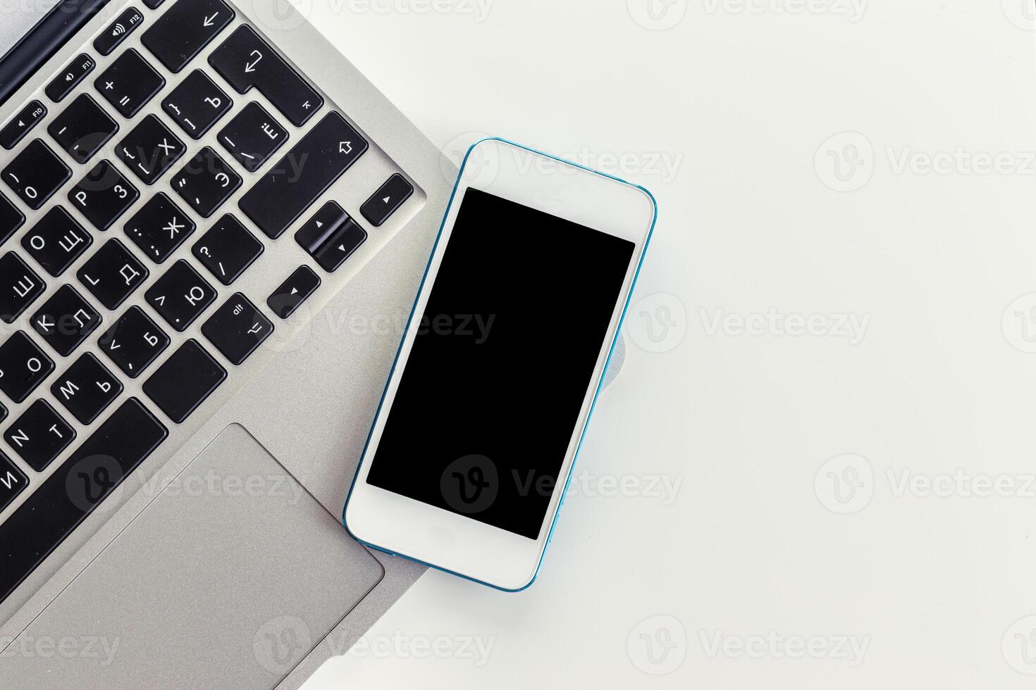 Smartphone resting on laptop keyboard in a modern workspace photo