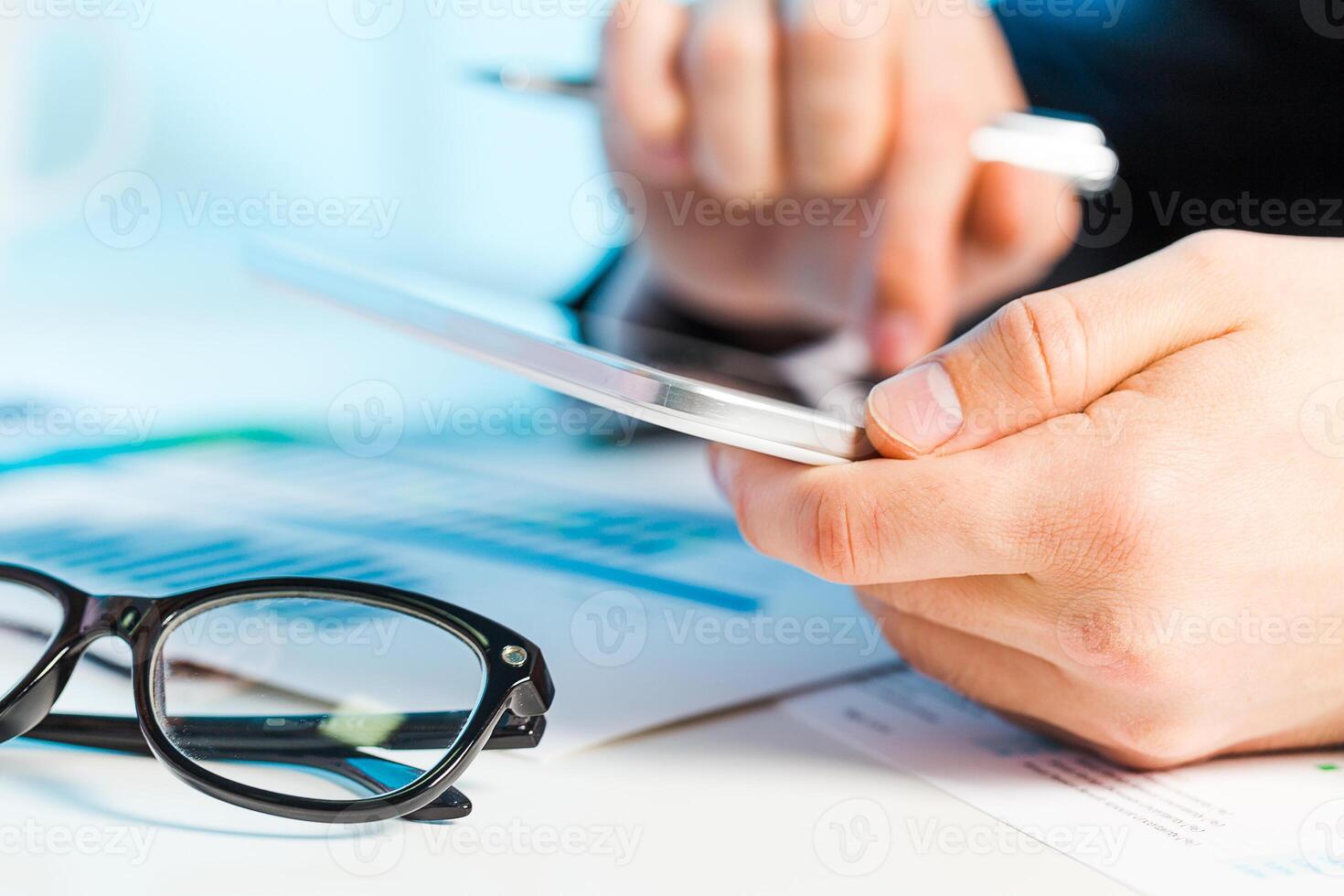 Hands holding a tablet while reviewing documents and using a pen during a professional meeting in an office photo
