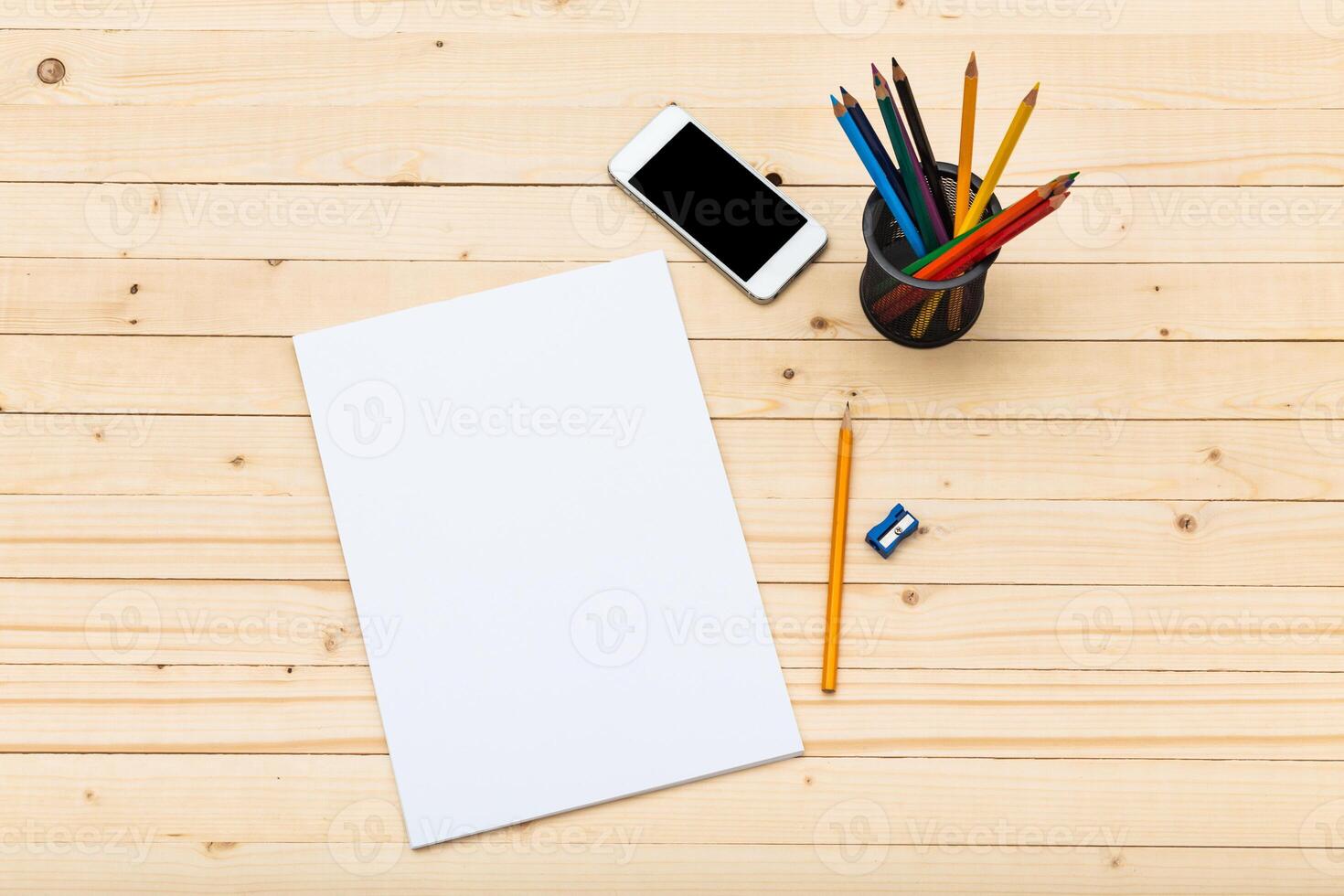Workspace setup with stationery, smartphone, and blank paper on wooden table photo