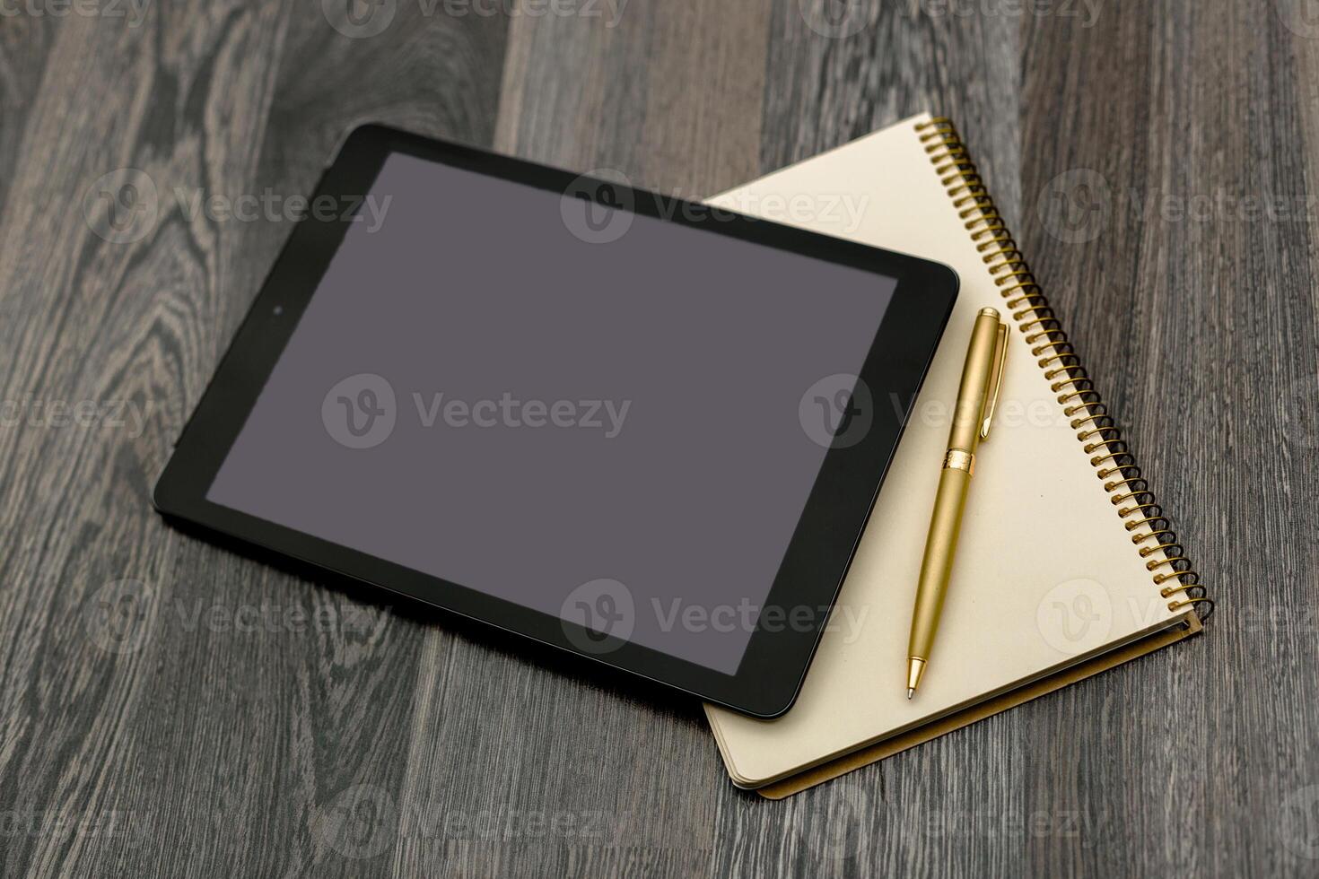 Tablet and notepad arranged on a wooden table for creative work or studying in a contemporary setting photo