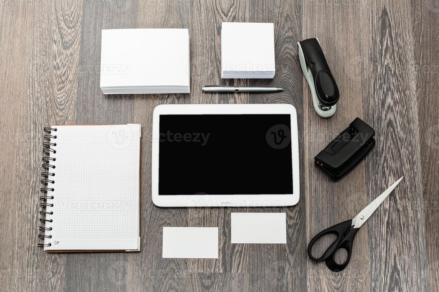 Workstation setup with tablet, notepad, stationery, and organizational materials arranged on wooden desk photo