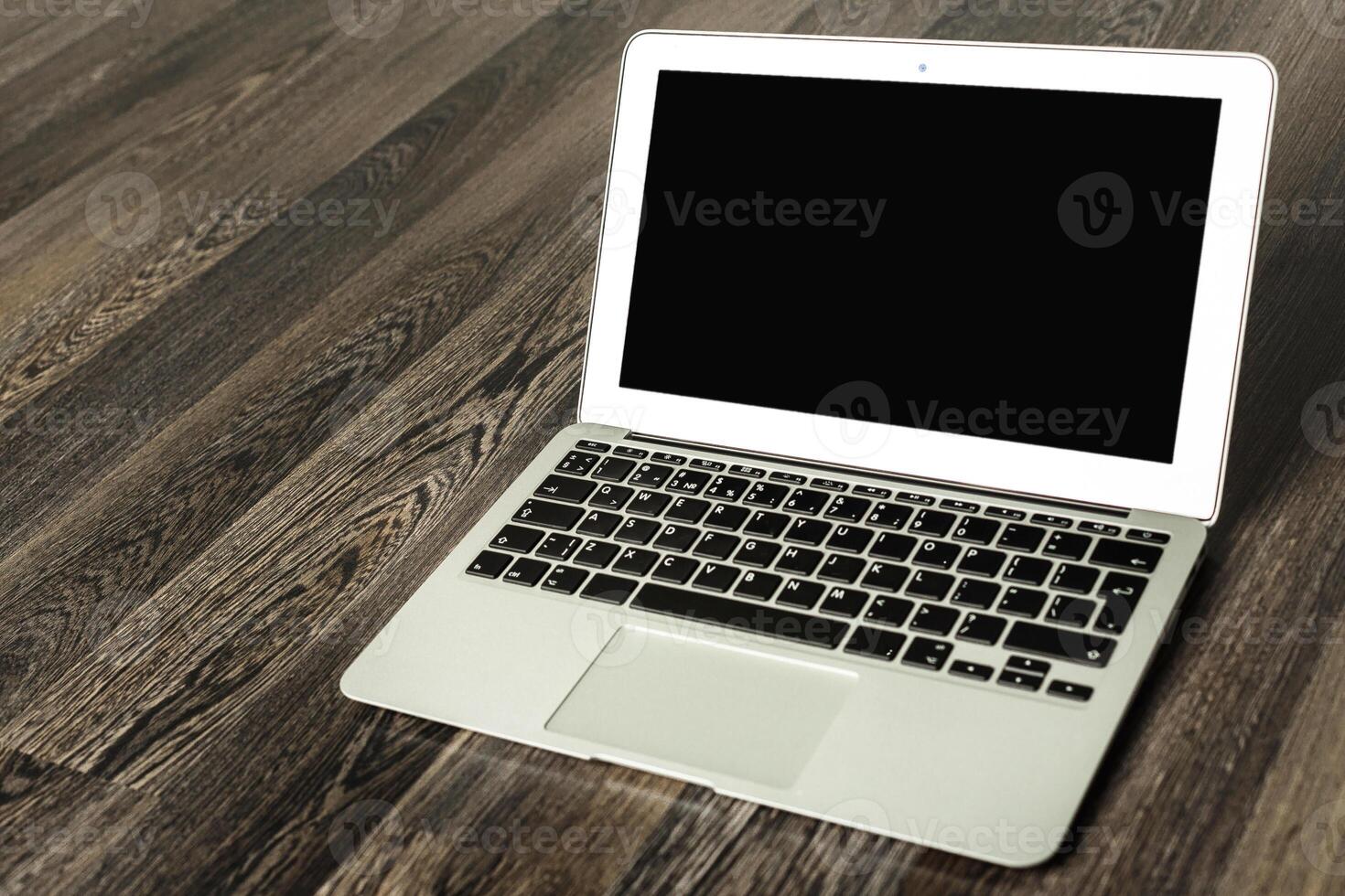 Laptop placed on wooden floor in a modern indoor setting during the day before any activity initiates photo