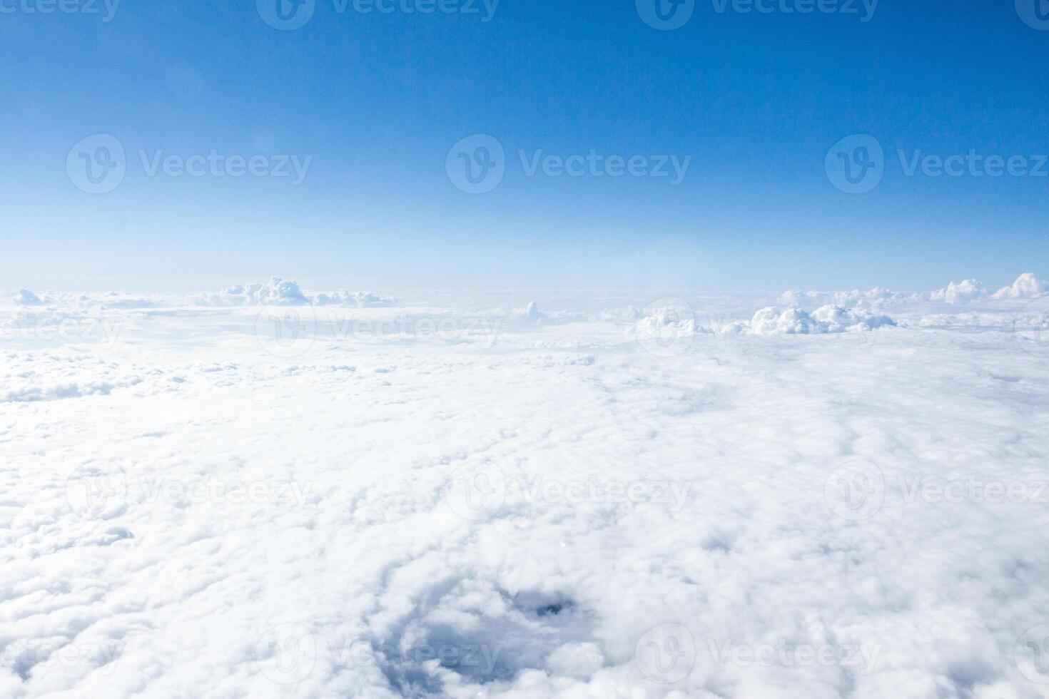 Expansive view of cloud cover under a clear blue sky captured from above during a sunny afternoon photo