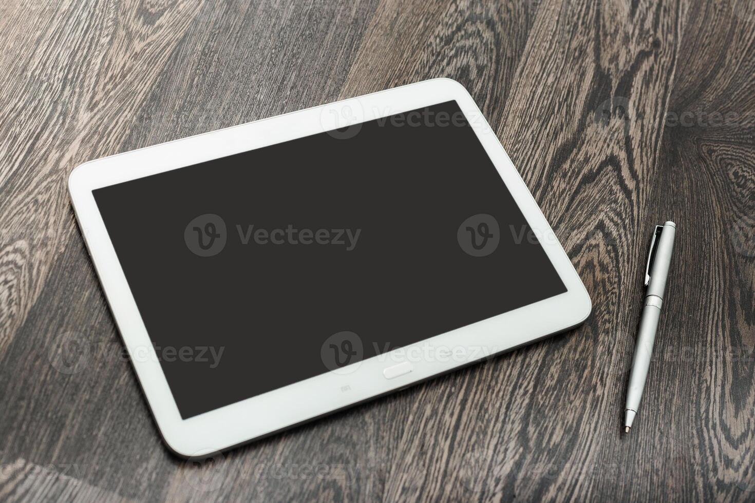 Tablet and pen on wooden table during work session in a modern office setting photo